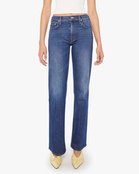 A person wearing Mother’s The Bookie Sneak in Perfectly Imperfect high-rise bootcut jeans, a white sleeveless top, and yellow pointed shoes, stands against a white background. Image is cropped from the shoulders down.