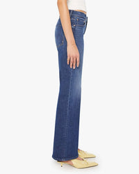 A person stands sideways in The Bookie Sneak in Perfectly Imperfect jeans by Mother, paired with a white sleeveless top and pointed yellow shoes, against a plain light background.