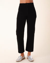 A person wearing Prairie Underground's Corduroy Carpenter Pant in Black stands against a plain light background. Only the lower torso and legs are visible, paired with silver loafers.
