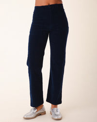 A person wears Prairie Underground's Corduroy Carpenter Pant in Midnight—high-rise, straight-leg, navy blue corduroy—paired with shiny silver loafers, shown waist to feet against a plain light background.