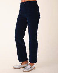 A person models Prairie Underground’s Corduroy Carpenter Pant in Midnight with metallic silver loafers, standing against a plain light background. The image is cropped from mid-torso to feet.