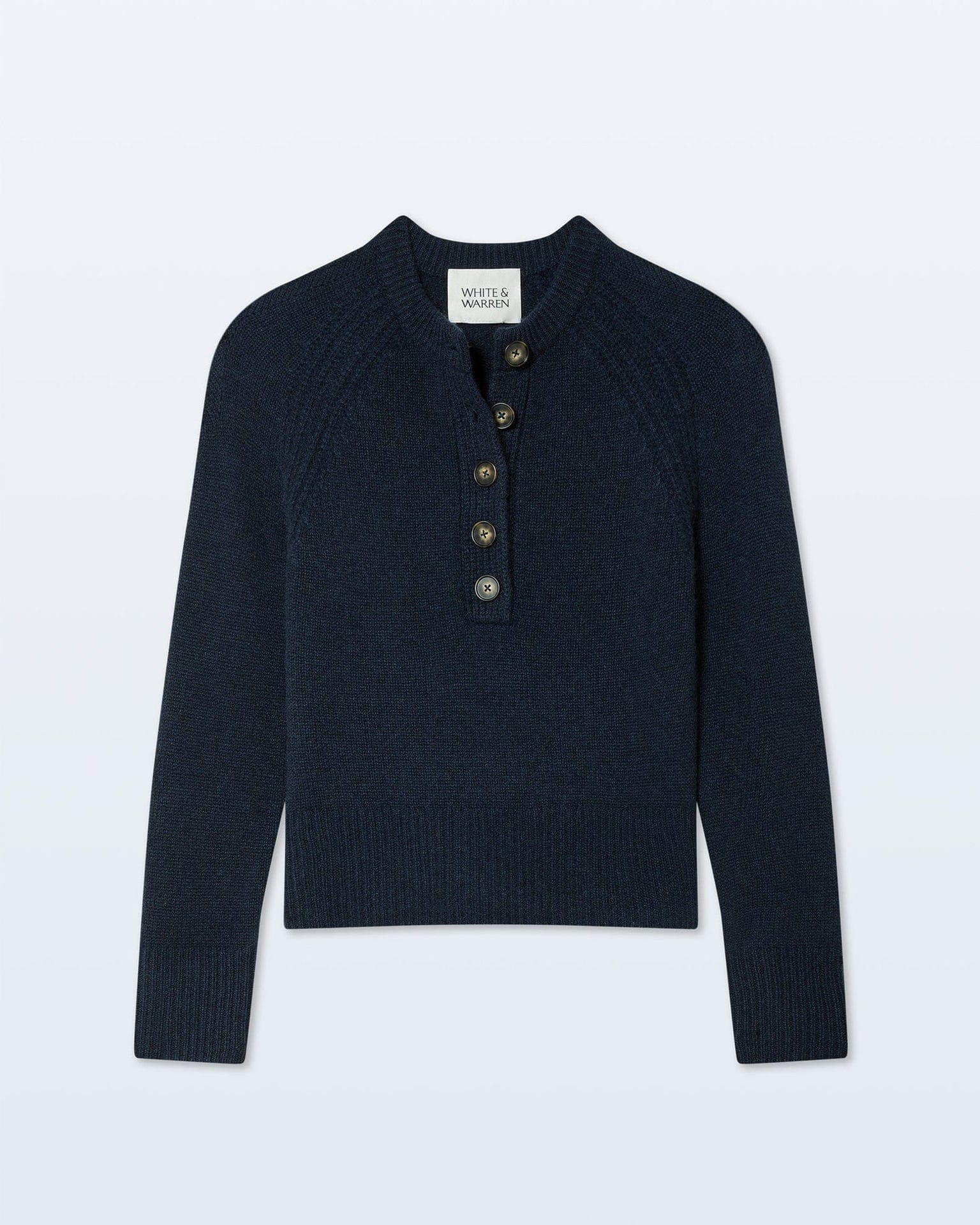 The White & Warren Cashmere Luxe Henley in Deep Navy is a long-sleeve cashmere sweater with ribbed hem and cuffs, a small collar, and a five-button henley-style placket featuring brown buttons.
