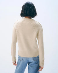 Person with short dark hair, seen from behind, wears the White & Warren Cashmere Luxe Henley in Natural Heather with light blue jeans, set against a plain, light background.