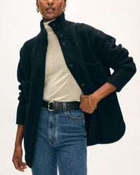 Wearing a cream turtleneck, Blue Jeans, black belt, and the Boucle Blend Luxe Jacket in Black by White + Warren, a person stands against a plain background with one hand on their hip.