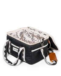The Premium Cooler Bag - Rivie Black by Business & Pleasure Co is a black-and-white canvas bag with a vintage look, patterned lining, dual handles, an external pocket, and a leather tag on a metal clasp. Eco-friendly and currently open and empty.