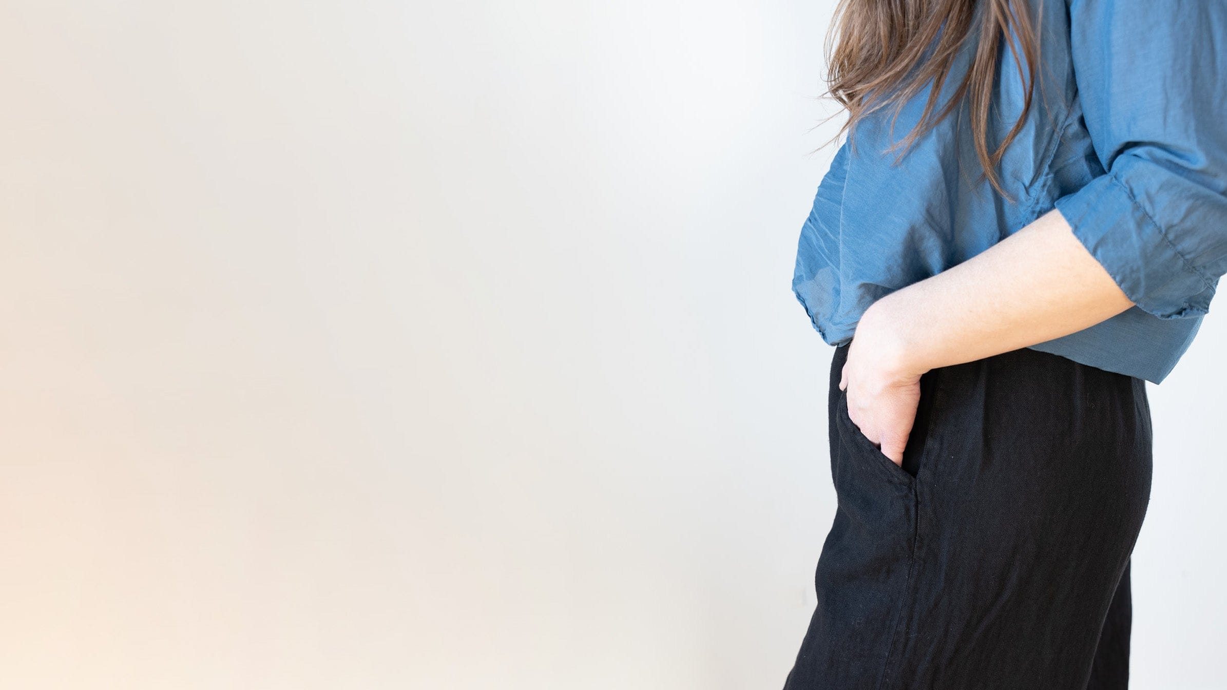 Person wearing a blue shirt and black pants against a light background