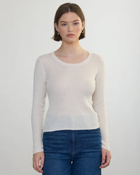 A woman with short brown hair wears a Margaret OLeary Scoop Neck Pullover in Ivory and blue jeans, standing facing the camera against a plain light background.