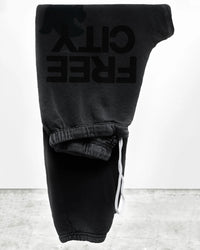 The FC Large Sweatpant in Volcano by Free City, featuring bold FREE CITY lettering, is shown upside down on a white background with a concrete floor.