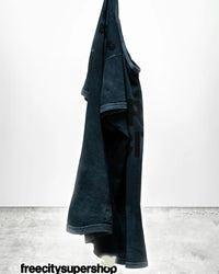 A dark blue FC thedoingofitisthebeingofit Supervintage S/S Tee in Volcano Powder by Free City hangs against a white background. “freecitysupershop” is in black text at the bottom on a gray concrete floor.