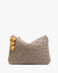 The Clare V. Heart Fob, a 14k gold-plated brass keychain with four heart-shaped charms, hangs elegantly from the strap of a taupe woven handbag as an accessory.