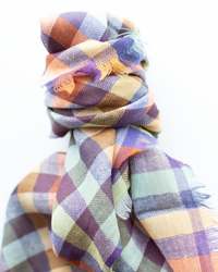 The Épice Plaid Wool Bandana in Orange, featuring a colorful check pattern, is loosely knotted and displayed against a white background.