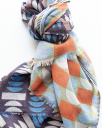 The Épice Pop Geo Wool Silk & Cashmere Scarf in Mauve features bold geometric patterns, shown tied in a loose knot against a white background.