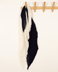 A Grisal Love Duo Mini scarf in Navy X Milk hangs on a wooden wall hook rack against a plain white background.