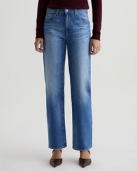 Model wearing The Brinley Straight in 13Ys Allure by AG Jeans, styled with a long-sleeve burgundy top and pointed brown shoes against a plain light background. Image is cropped at the shoulders.