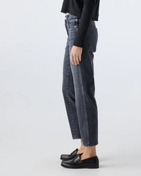 Side view of a person wearing AMO’s Libby in Smokin dark wash high-waisted straight-leg jeans, black loafers, and a black long-sleeve top against a plain light background.