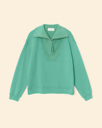 The XiRENA Kat Sweatshirt in Field Green is a relaxed-fit, 100% cotton long-sleeve pullover with a half-zip collar, shown on a beige background.