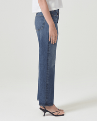 A person stands in profile wearing AGOLDE 90s Jean in Imagine, a white top, and black heeled sandals against a plain white background.