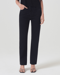 A person wearing AGOLDE 90s Pinch Waist in Crushed jeans and black strappy sandals stands against a plain white background, with the upper body partly cropped out of the image.