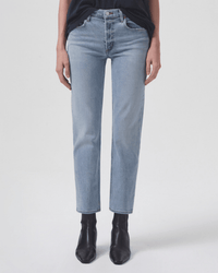 A person wearing AGOLDE’s Kye in Diversion jeans, a black top, and black ankle boots stands against a plain light background. The cropped image shows the mid-rise, straight-leg denim from shoulders to feet.