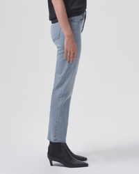 Someone stands sideways against a plain white background, wearing AGOLDE's Kye in Diversion jeans—a mid-rise, vintage-inspired straight-leg style—with a black top and black ankle boots.