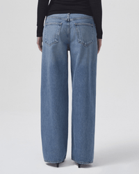 A person shown from the back against a plain light background wears AGOLDE's Low Slung Baggy in Libertine denim and a black long-sleeve top.