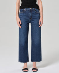 A person models the AGOLDE Ren in Echo high-rise wide leg jeans, paired with a black sleeveless top and black open-toe sandals. Only the lower torso and legs are visible against a plain light background.