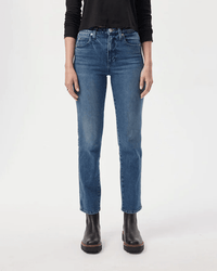 A person wearing a black long-sleeve top, black ankle boots, and AMO Chloe Crop in True Love blue high-rise straight leg jeans stands against a plain white background.