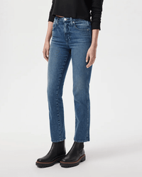 A person wearing the AMO Chloe Crop in True Love, paired with a black long-sleeve top and black ankle boots, stands against a plain light background, highlighting these classic straight-leg jeans with effortless style.