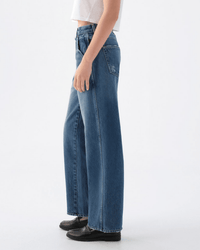 A person in a white cropped top, AMO Jocelyn Shaped Trouser in Two Timing, and black shoes stands sideways against a plain white background.
