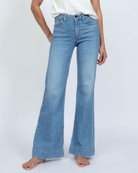 A person wearing ASKK NY Juniper Keel Over jeans in Keel Over stands barefoot against a plain white background, paired with a white T-shirt. Their face is not visible.