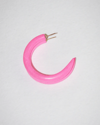 A single Runaway Bunny C Hoop in Small by B&L, a pink crescent-shaped mango wood earring with gold posts, rests on a white surface, highlighting the artisanal charm of handmade jewelry.