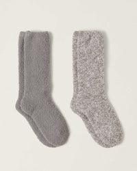 Two pairs of Barefoot Dreams CC 2 Pair Sock Set in Pewter Multi are laid side by side—one in solid gray, the other in a gray and white mix—showing their soft, textured look against a plain light background.