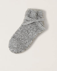 A single Barefoot Dreams CC Heathered Tennis Sock in Moonbeam/White with a textured look, wrapped in a gray "BABY, DREAMS" ribbon. This tennis-height sock is shown on a plain light background.