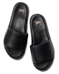 A pair of beek.. Puffbird in Black slide sandals with wide straps and cushioned, molded arch support soles, shown on a white background. "beek.." is printed in gold on each sandal’s heel.