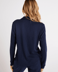 A person with long, wavy, light brown hair is shown from the back wearing Bella Dahl's Button Up Knit Top in Endless Sea against a plain white background.