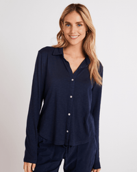A woman with long, wavy blonde hair smiles at the camera, wearing the Bella Dahl Button Up Knit Top in Endless Sea against a plain light background.