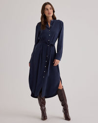 A woman wearing the Bella Dahl Flowy Hem Maxi Dress in Endless Sea, styled with tall brown heeled boots, stands against a plain light background.