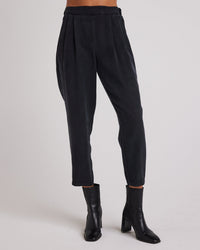 A person wears the Bella Dahl Nico Clean Waist Slouchy Trouser in Black, styled with black ankle boots, against a plain light background. The upper body is not visible.