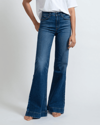 A person in a white t-shirt and ASKK NY Juniper Wide Leg in Auburn jeans stands barefoot against a plain light background.