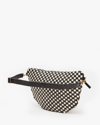 The Clare V. Grande Fanny in Black & Cream Woven Checker features a black adjustable strap and gold hardware, shown against a white background.