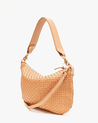 The Clare V. Moyen Messenger in Bisque Woven Checker, a tan handwoven leather shoulder bag with a wide adjustable strap and gold-tone hardware, is displayed on a plain white background.