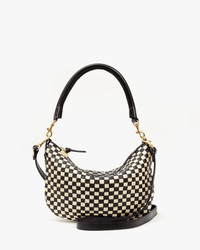 The Clare V. Woven Checker Petit Moyen Messenger in Black & Cream features a crescent shape, black leather handle, gold hardware, and a detachable black shoulder strap, shown against a white background.