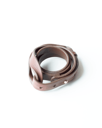 The Depalma Handsewn Nuova 3/4 inch Single Wrap in Bark/Brass is a brown leather bracelet with metal studs and a brass button fastener, coiled neatly on a white surface.