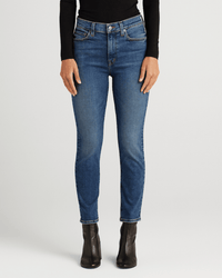 Wearing Edwin’s Bree in Abbot jeans, a person stands against a plain light background. Only their lower torso and legs are visible, paired with a black long-sleeve top and black ankle boots.