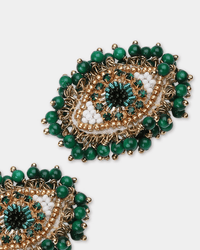 The Milos Eye Earrings in Green by Olivia Dar feature eye-shaped beaded designs in green, gold, black, and white with a green and gold decorative border; two earrings are partially visible on a white background.