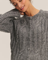 A woman wearing the Allison Long Sleeve Crew Cardi in Heather Grey by Velvet by Graham & Spencer smiles gently with her eyes closed, hand resting on the back of her head.