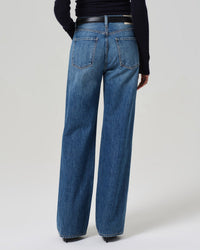 Person wearing Citizens of Humanity Annina High Rise Wide Leg 30in jeans in Sunland and a black long-sleeve top, viewed from the back against a plain light background.