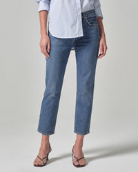 Wearing Citizens of Humanity's Charlotte High Rise Straight in First Class jeans, an untucked light blue and white striped button-down shirt, and brown strappy heeled sandals, a person stands against a plain light background.