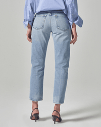 Someone stands facing away against a plain light background, wearing Citizens of Humanity's Isla Low Rise Straight in Spector—light blue, vintage fit denim straight-leg jeans—paired with a light blue untucked shirt and black heeled sandals.