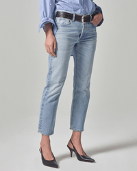 Model wears Citizens of Humanity Isla Low Rise Straight in Spector, styled with a blue rolled-sleeve shirt, black belt, and black pointed-toe heels. Cropped below the shoulders, standing against a plain light background.